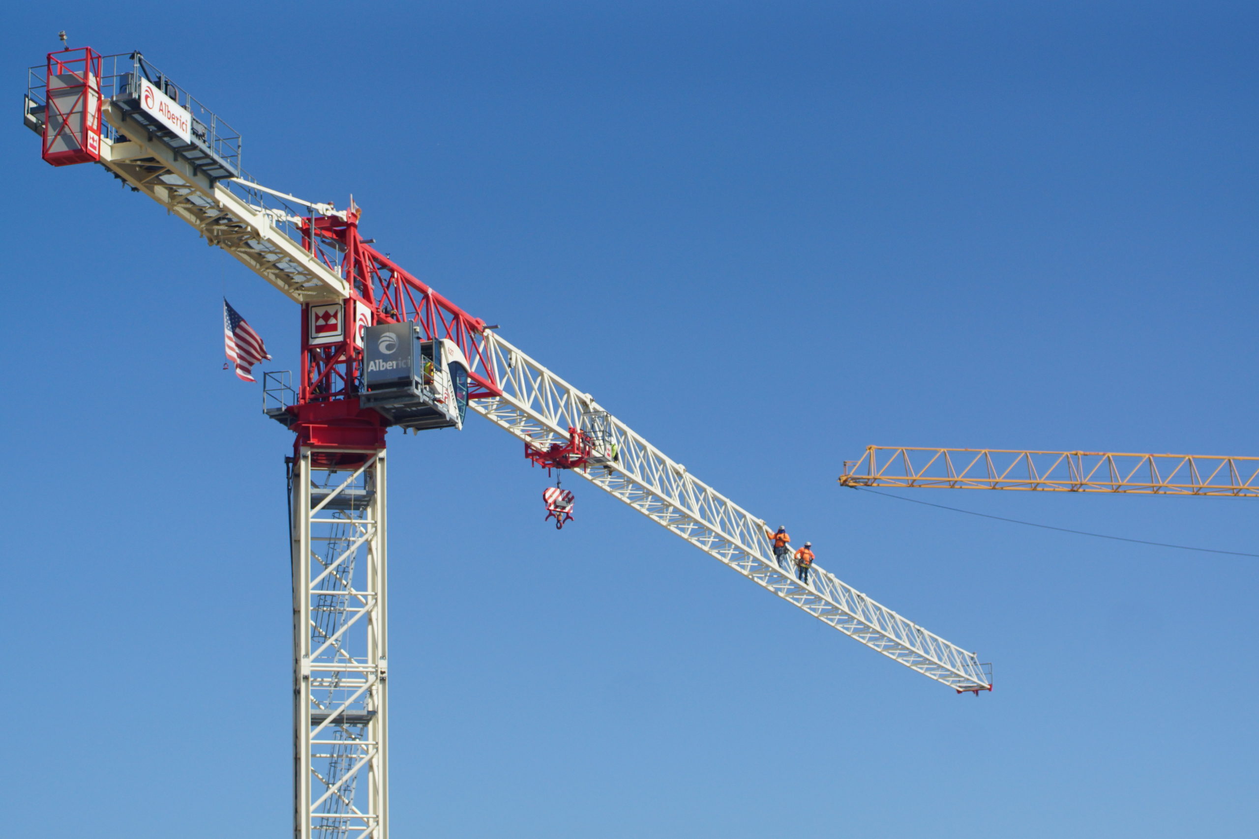 Image of workers scaling tower crane to begin dismantling it.