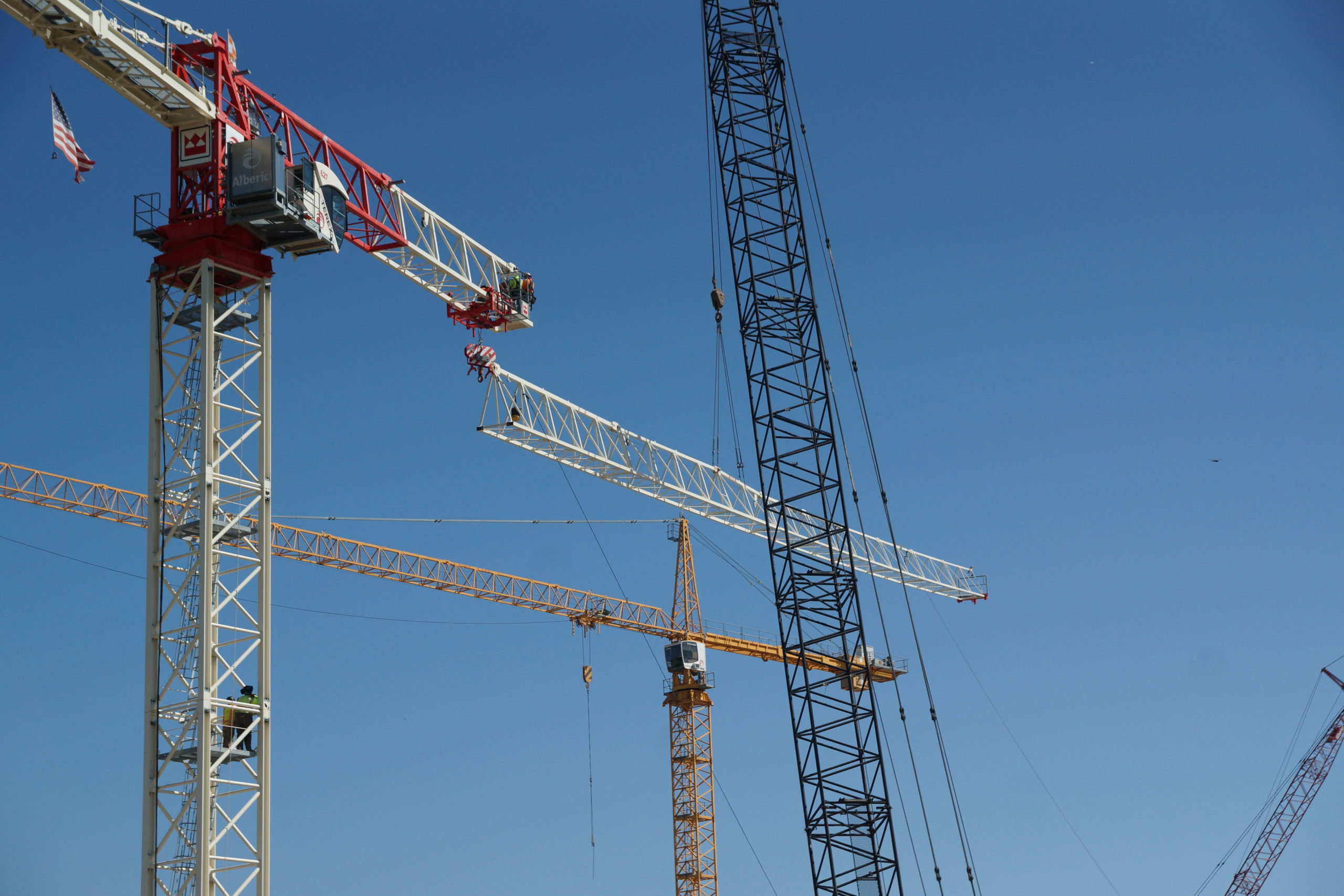 Image of tower crane with part of the boom being removed.