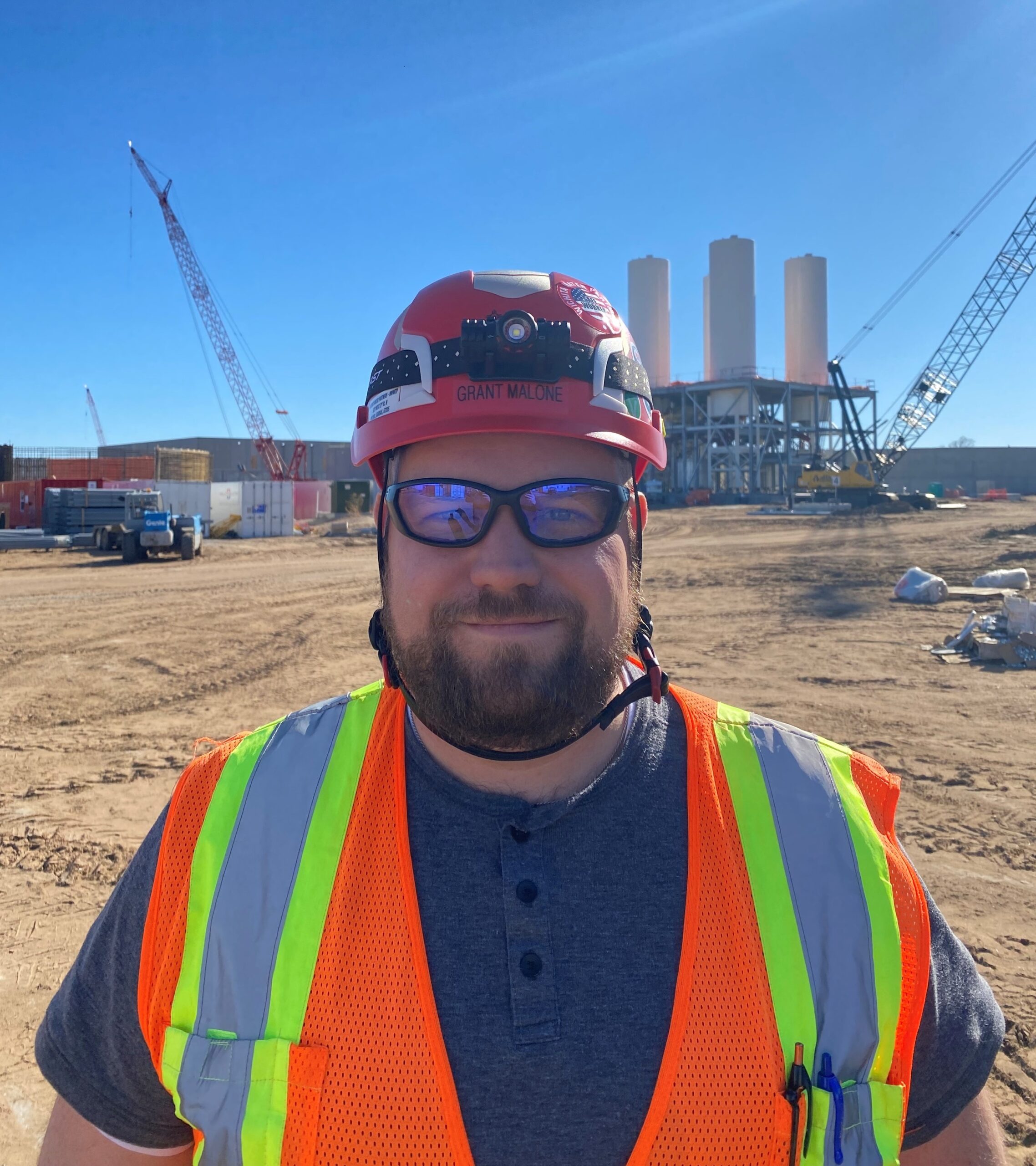 Project Manager Grant Malone wears a hard hat, safety goggles and a neon orange and yellow safety vest on site at Wichita’s Northwest Water Facility.